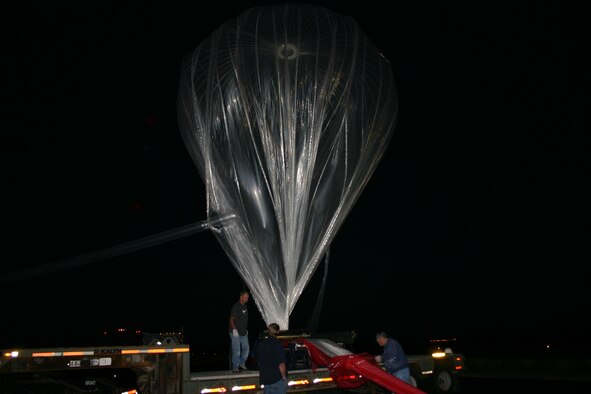 Members of the High-Altitude Balloon Program prepare a helium balloon and its payload for launch.