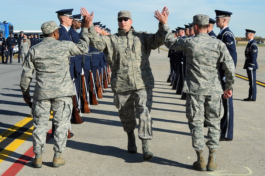 Staff Sgt. Peter Barker, 1st Helicopter Squadron radio operator, runs through a cordon made up of members of the Air Force Honor Guard and high fives Colonel Ken Rizer, 11th Wing commander, and Chief Master Sgt. Anthony Brinkley, 11th Wing command chief, during the 11th Wing commander's call on the Joint Base Andrews flightline Nov 2. The commander's call highlighted the unique assets of the 11th Wing to its members after the recent mission move, including the 1st Helicopter Squadron, the Air Force Honor Guard, and the Air Force Band. (U.S. Air Force photo by Senior Airman Melissa Brownstein)