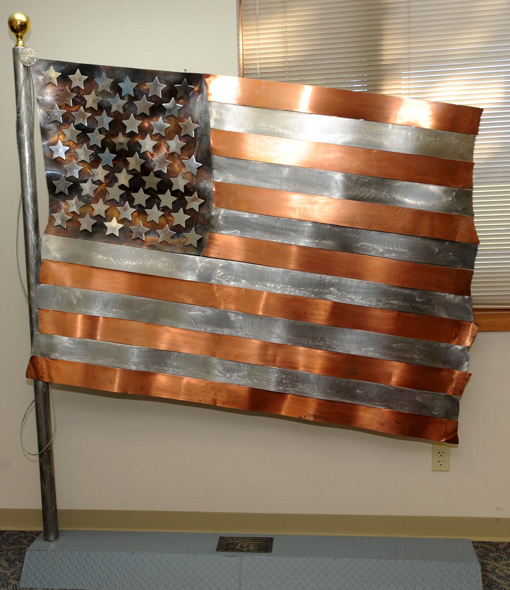 The copper and stainless steel American flag sculpture was donated to the Grand Forks Air Force Base Airman Leadership School by the 319th Maintenance Group during a ceremony Nov. 4 at the ALS building.  The 319th MXG donated the flag sculpture to the school because the maintainers wanted to leave a piece of their heritage behind as the 319th Air Refueling Wing mission continues to draw down.