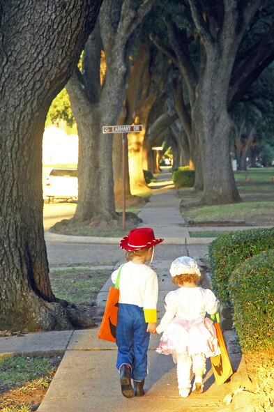 BARKSDALE AIR FORCE BASE, La. -- Emma Grace, 4, and Aubrey, 2, daughters of Maj. Christopher Strong deployed in support of Operation Iraqi Freedom, hold hands as they trick-or-treat down Barksdale Boulevard Oct. 31. Hundreds of children in costume lined the streets of Barksdale's four housing areas between the hours of 6 p.m. and 8 p.m. Halloween night in search of sweet treats. (U.S. Air Force photo/Senior Airman Joanna M. Kresge)