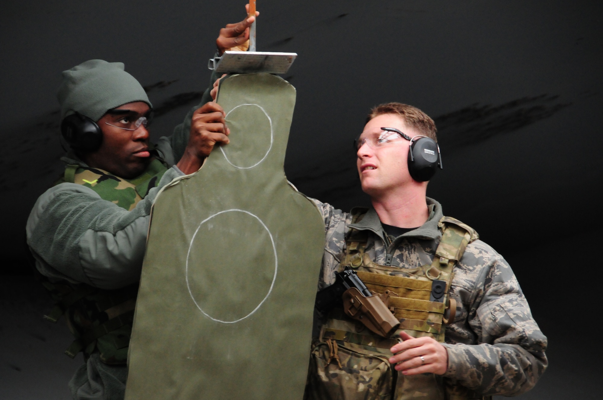 ROYAL AIR FORCE FELTWELL, England – Capt. Jason Rodgers (left), 56th Rescue Squadron Chief of HH-60 standardization and evaluation, helps Staff Sgt. Benjamin Opare Abetia, 56th Rescue Squadron Resource Management, set up his target in preparation for the small arms qualification course Nov. 2. Practice rounds were fired prior to certification to ensure students were comfortable and confident to fire their weapon. (U.S. Air Force photo/Airman 1st Class Erin Zabarnick) 