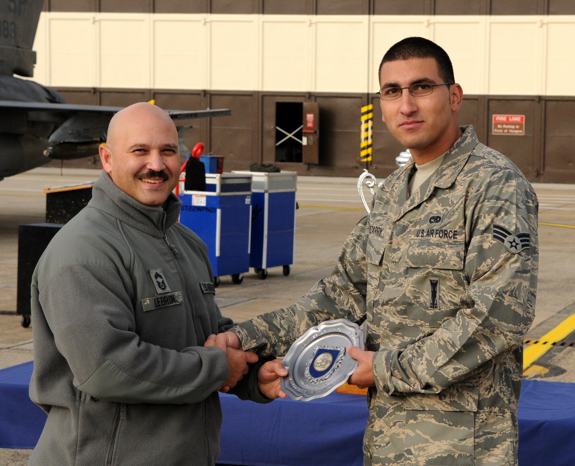 SPANGDAHLEM AIR BASE, Germany – Chief Master Sgt. Steve Lebron, United States Air Force in Europe weapons load crew functional area manager, presents the Jammer Driver of the Quarter award to Senior Airman Marcus Irizarry, 52nd Aircraft Maintenance Unit weapons load crew member, Nov. 2. Irizarry won a competition for MJ-1 drivers, which consisted of navigating through a course of road cones with the fastest time while hitting the fewest amount of cones. (U.S. Air Force photo/Airman 1st Class Matthew B. Fredericks)
