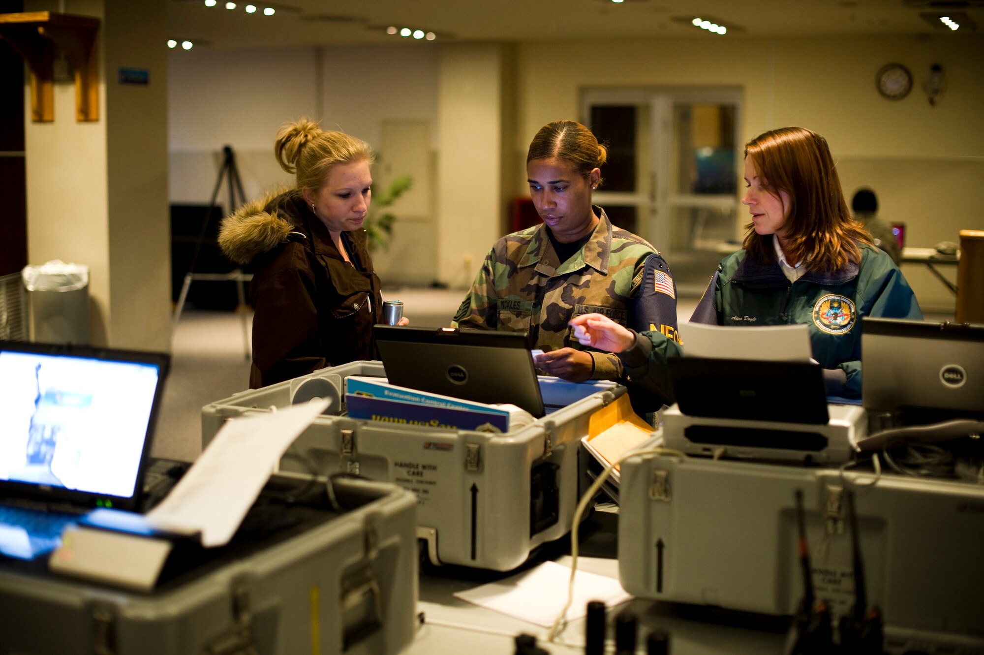Andrea Slayton (left), U.S. Air Force Staff Sgt. Trisha Mickles and Alica Doyle, Noncombatant Evacuation Operations Tracking System administrators, process simulated incoming evacuees in the Mokuteki Community Center during an operational readiness exercise at Misawa Air Base, Japan, Nov. 4, 2010. The tracking system allows bases to maintain accountability of evacuees and make sure they arrive at their destination. (U.S. Air Force photo by Staff Sgt. Samuel Morse/Released)