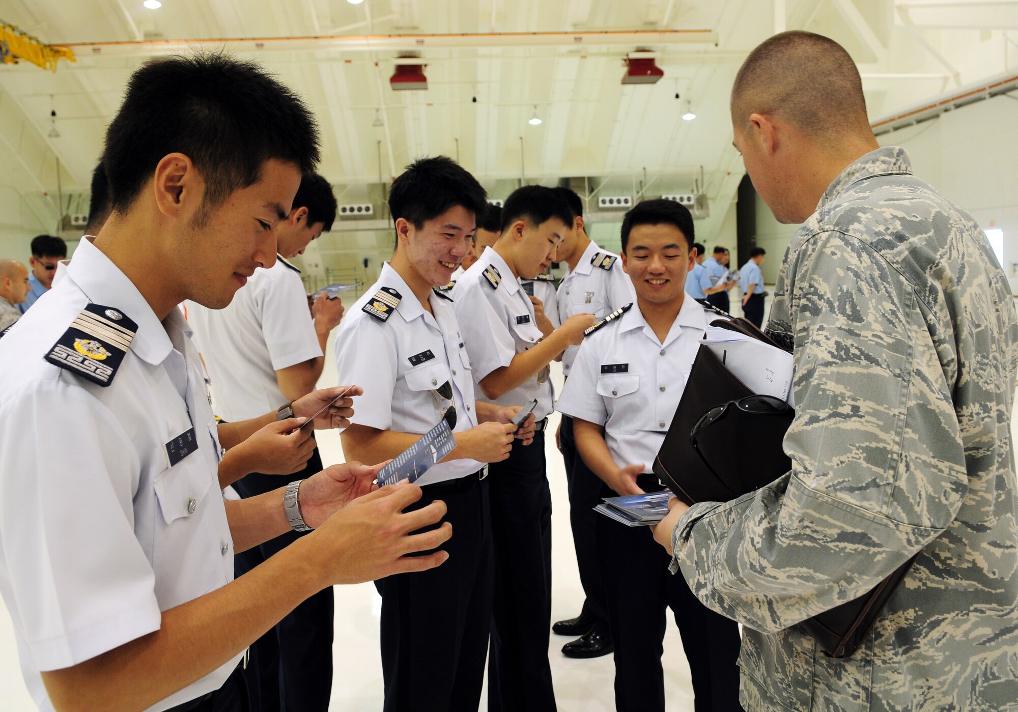 U.S. Air Force 1st Lt. Justin Shetter, a maintenance officer from the 36th Expeditionary Aircraft Maintenance Squadron, hands out RQ-4 Global Hawk aircraft information cards to Republic of Korea Air Force Academy Cadets during a visit to Andersen Air Force Base, Guam, Nov. 4. The purpose of their visit here and Joint Region Marianas Naval Base Guam was to promote and strengthen the close ties between the allied nations. (U.S. Air Force photo/ Senior Airman Nichelle Anderson)