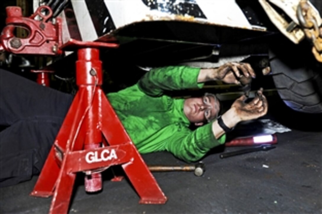 U.S. Air Force Airman Bryant Scallorn performs a front-end tie rod adjustment on an aircraft tow tractor in the hangar bay of the aircraft carrier USS Harry S. Truman in the Arabian Sea, Nov. 2, 2010. Scallorn is an aviation support equipment technician.