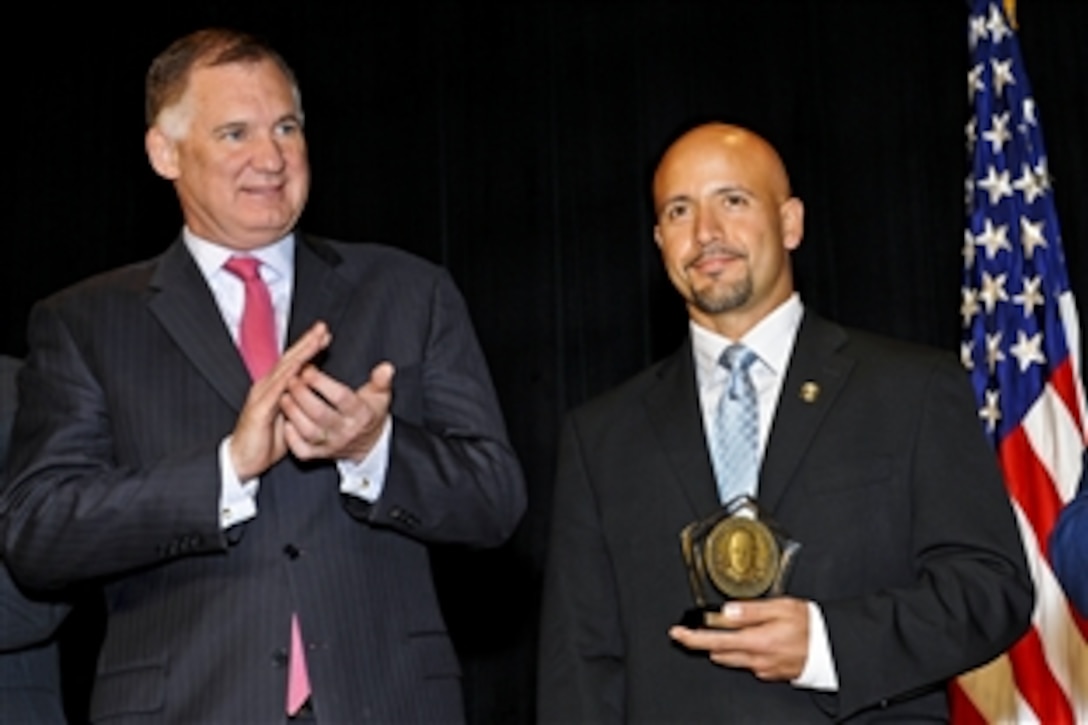 Deputy Secretary of Defense William J. Lynn III applauds Manuel A. Fajin after presenting him the 6th annual Defense Department's David O. Cooke Award for Excellence in Public Administration during ceremonies at the Pentagon, Nov. 4, 2010. Fajin is a special agent with Force Protection Detachment Colombia, Air Force Office of Special Investigations.