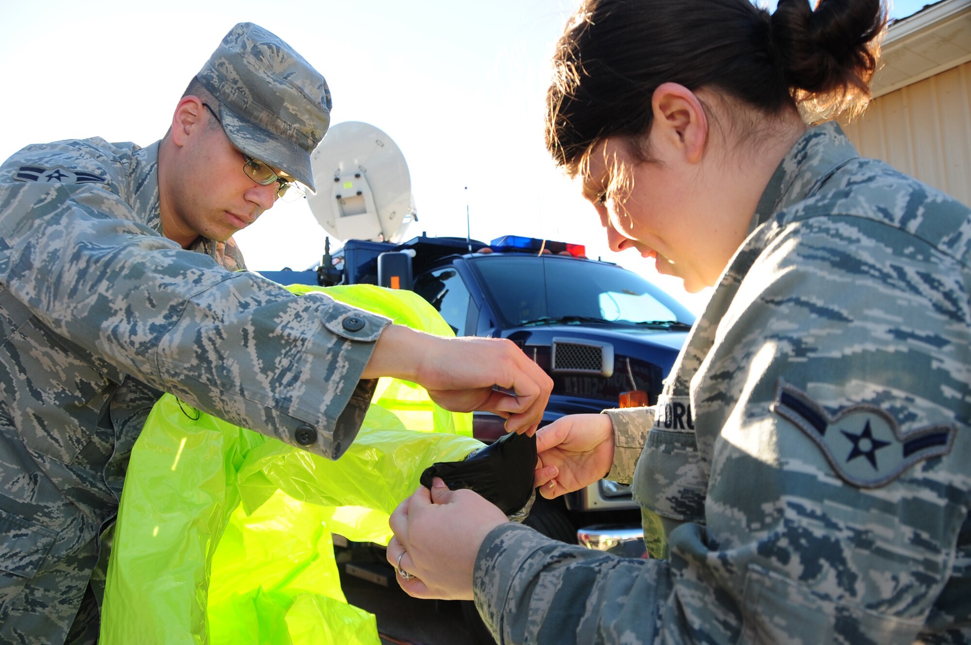 ELLSWORTH AIR FORCE BASE, S.D. - Airman 1st Class Matthew Hung, 28th Civil Engineering Squadron emergency management journeyman, puts on a chemical protection suit while Airman Francheska Rebardi, 28 CES emergency management apprentice, assists him during a joint training mission with the Army National Guard and the Rapid City Fire Department in Rapid City, S.D., Nov 4.  Ellsworth Airmen utilize this training scenario to improve their skills not only with their job but also improve their skills working with other agencies. (U.S. Air Force photo/Senior Airman Anthony Sanchelli)

