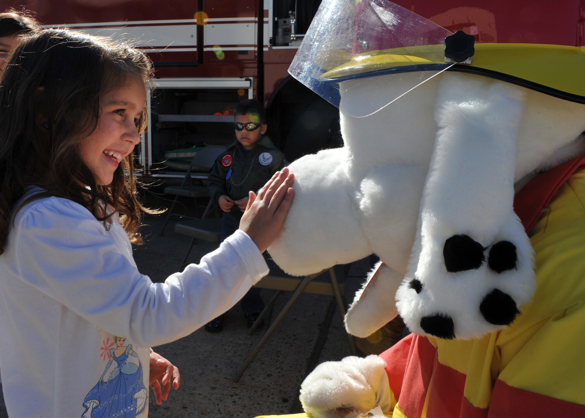 Alessia Savoia, daughter of 1st Lt. Stefano Savoia, an Italian exchange pilot with the 41st Airlift Squadron, pets Sparky the Fire Dog during Operation Kids Understanding Deployment Operations Oct. 29. Operation K.U.D.O.S. is a program designed to give children the opportunity to experience what happens when their parents deploys. (U.S. Air Force photo by Senior Airman Gul Crockett)