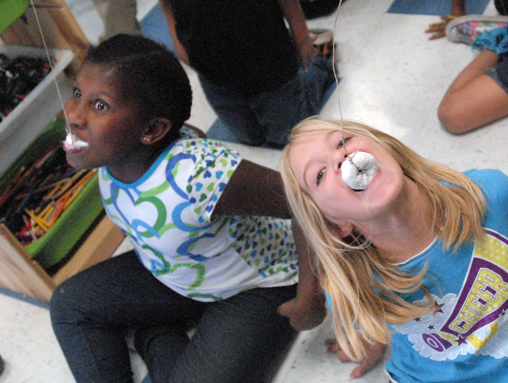 GOODFELLOW AIR FORCE BASE, Texas - From left: Dominique Cobbins, 9, and Audrey Gebauer, 7, race against either other to see who can eat the dangling donut off the string first during the Kids Fall Festival at the School Age Center Nov. 4. Military youths from the School Age and Youth Center organized and ran all the games held at this year's event. (U.S. Air Force photo/Connie Hempel)