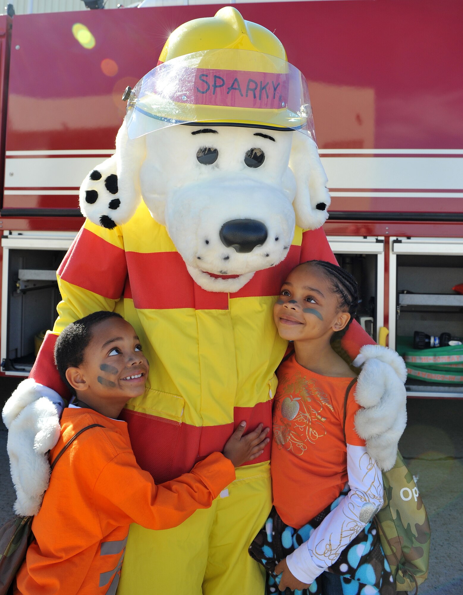 Terell and Tiana Whitehead, children of Yolanda Whitehead, 19th Force Support Squadron, hug Sparky the Fire Dog during Operation Kids Understanding Deployment Operations Oct. 29. Operation K.U.D.O.S. is a program designed to give children the opportunity to experience what happens when their parents deploys. (U.S. Air Force photo by Senior Airman Gul Crockett)