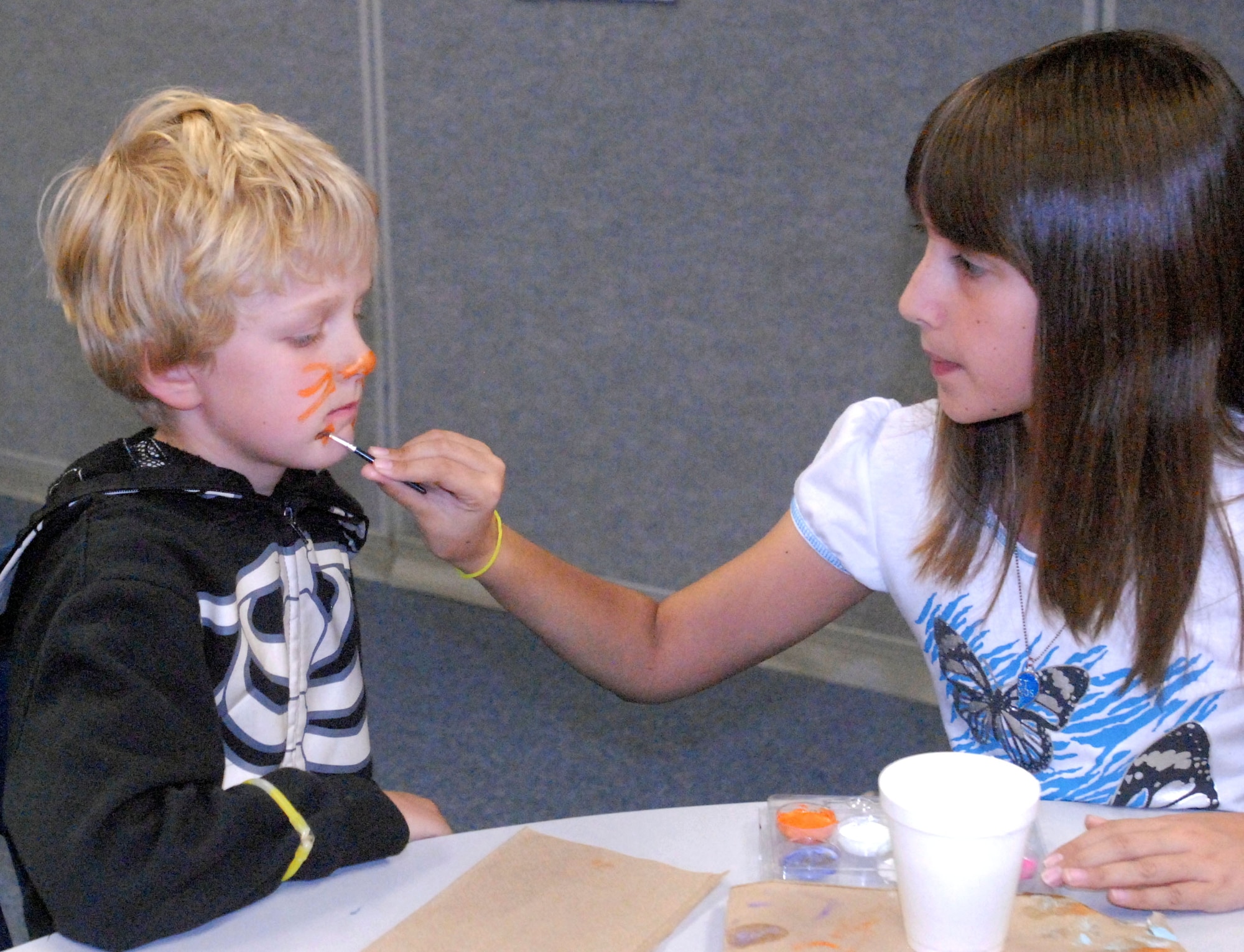 GOODFELLOW AIR FORCE BASE, Texas - Liam Meador, 7, gets his face painted by Taylor Lane, 9, during the Kids Fall Festival at the School Age Center Nov. 4. Military youths from the Youth Center and School Age organized and ran all the games held at this year's event. (U.S. Air Force photo/Connie Hempel)