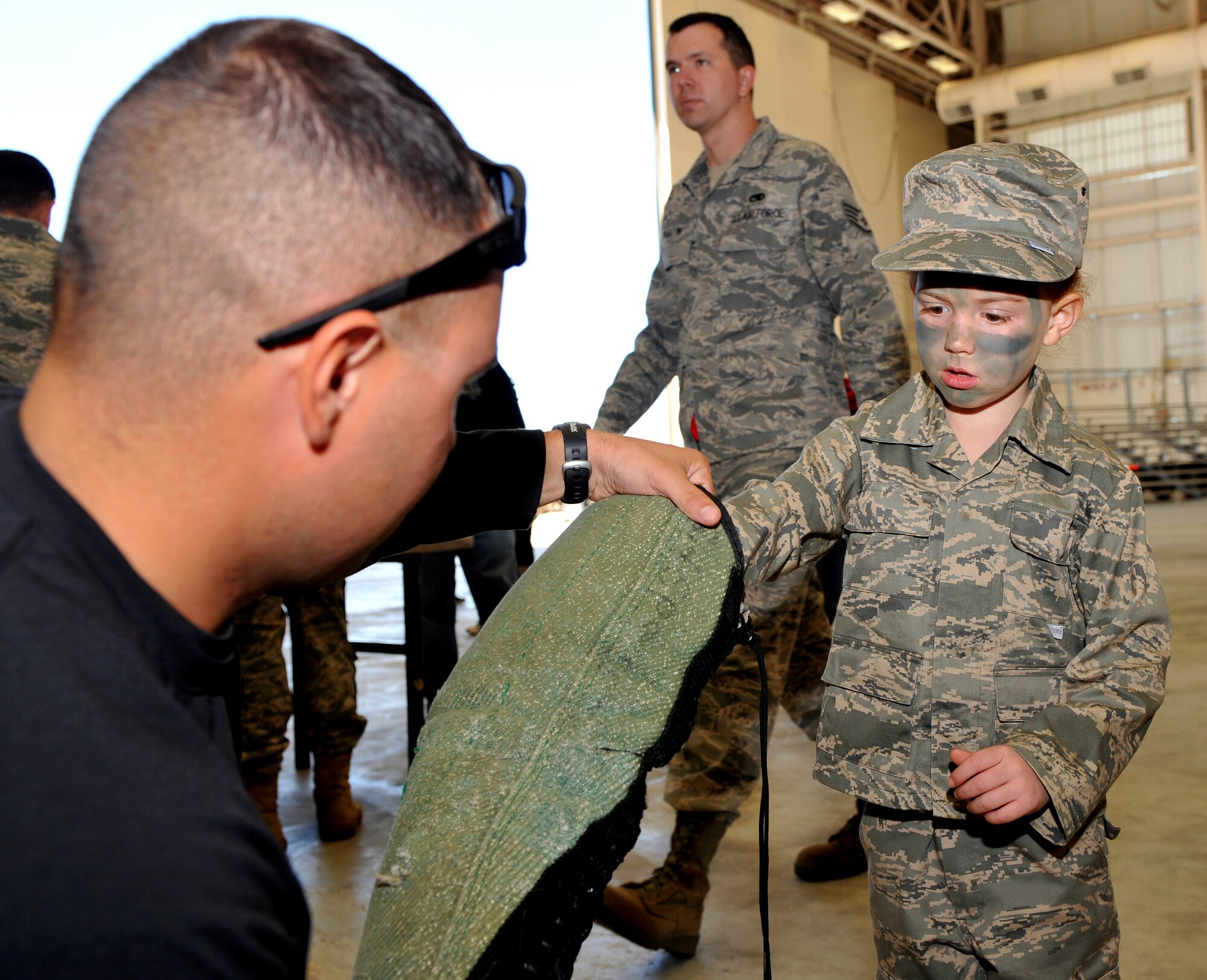Senior Airman James Campana, 19th Security Forces Squadron K-9 handler, helps Kassey Daugherty, daughter of Staff Sgt. Kenneth Daugherty, 19th Communications Squadron unit deployment manager, try on a “bite suit” during Operation Kids Understanding Deployment Operations Oct. 29. Operation K.U.D.O.S. is a program designed to give children the opportunity to experience what happens when their parents deploys. (U.S. Air Force photo by Senior Airman Gul Crockett)