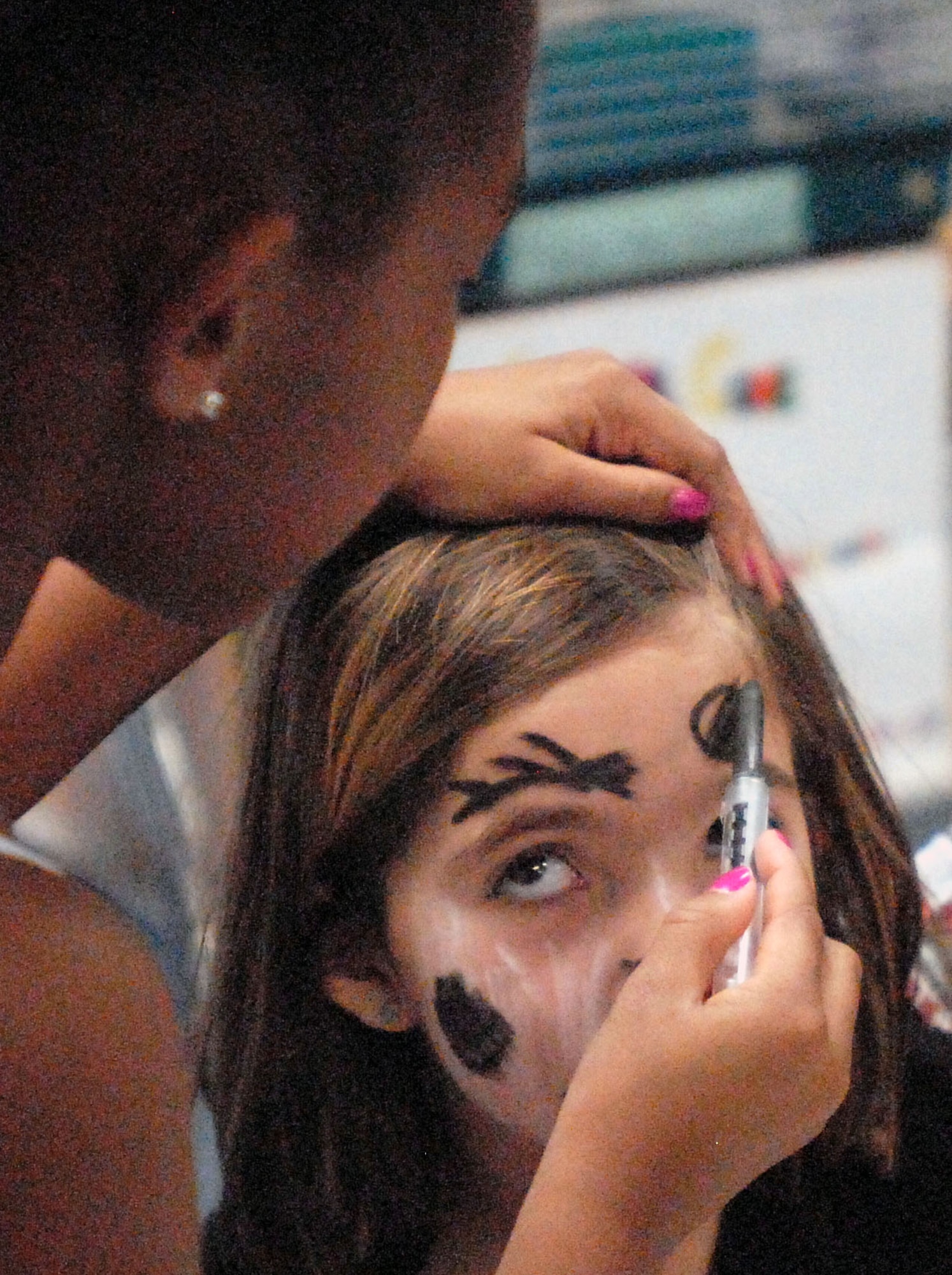 GOODFELLOW AIR FORCE BASE, Texas -- Elizabeth Maldonado, 8, gets her face painted by Uniyah Briscoe, 7, during the Kids Fall Festival at the School Age Center Nov. 4.  Military youths from the Youth Center and School Age organized and ran all the games held at this year's event. (U.S. Air Force photo/Connie Hempel)