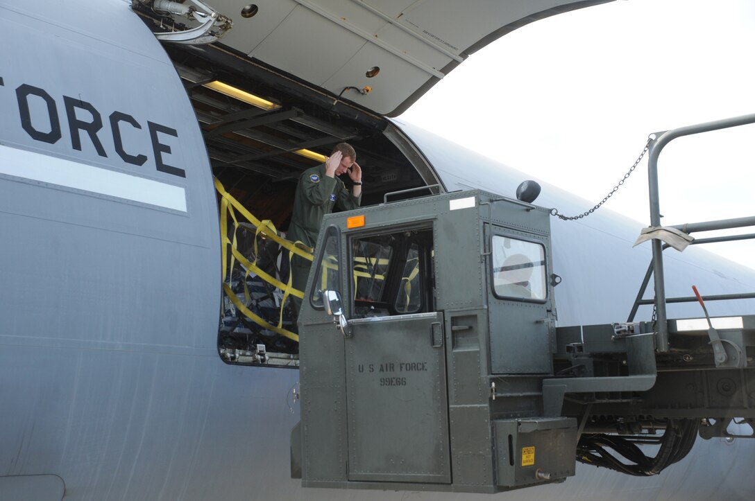SOTO CANO AIR BASE, Honduras --  A KC-10 Extender aircrew member from Joint Base McGuire-Dix-Lakehurst, N.J., guides in the driver of a Tunner to begin unloading 13 pallets of humanitarian aid here Oct. 21. The Joint Base MDL aircrew and 612th Air Base Squadron Air Terminal Operations Center worked together to get the humanitarian supplies delivered to local charities. (U.S. Air Force photo/Tech. Sgt. Benjamin Rojek)