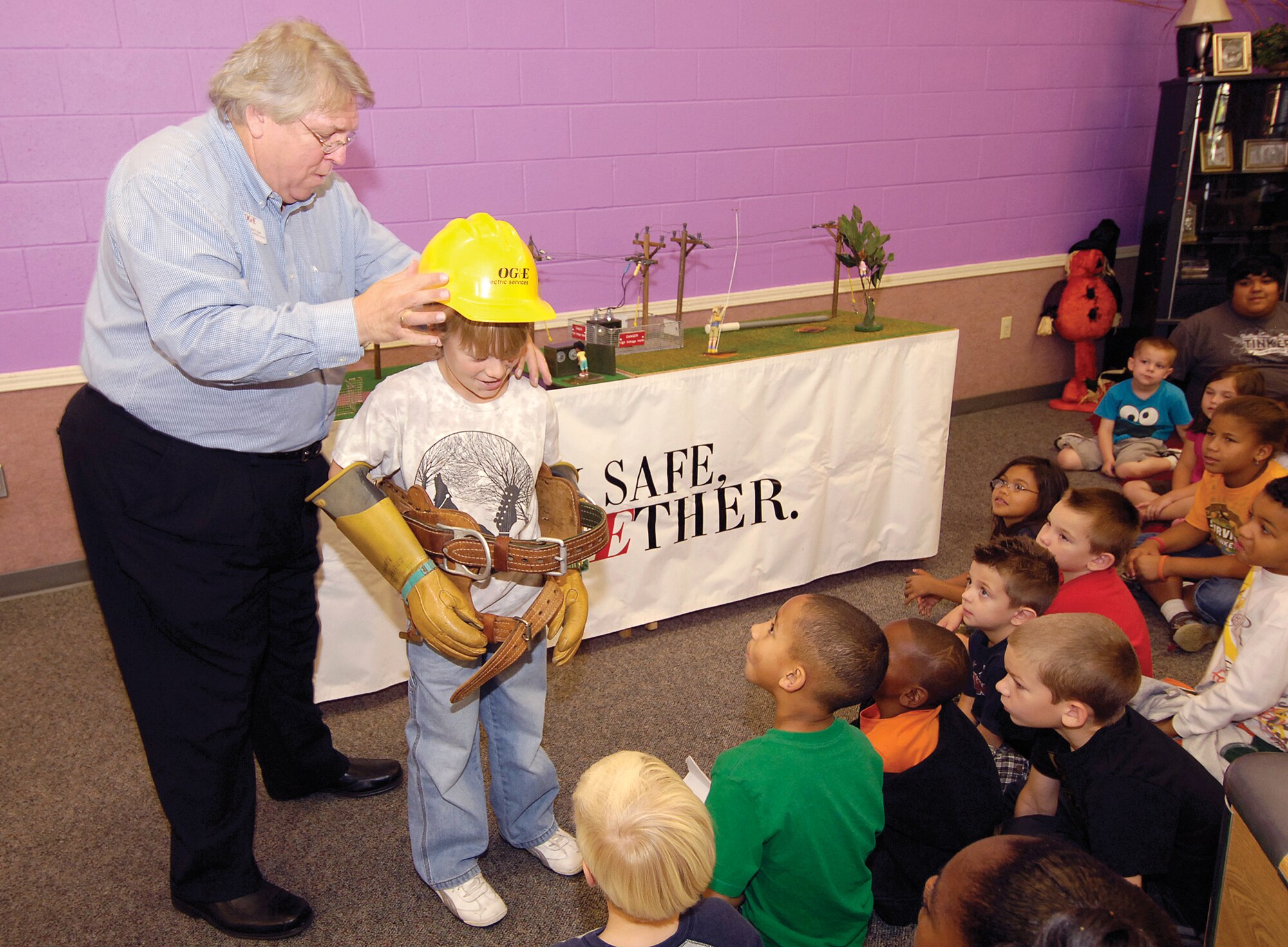 Third-grader Adam Conley tries on the gloves and gear of an Oklahoma Gas and Electric Company line man during a recent presentation to Tinker Youth Center children.  Saving electricity and staying safe around current-producing things was the presentation given by OGE representative John Koons. (Air Force photo by Margo Wright)