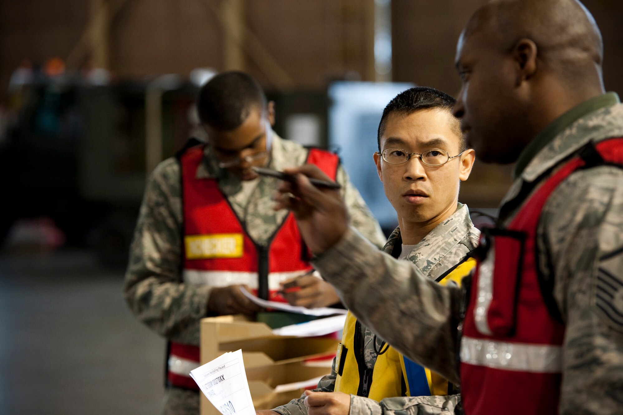 U.S. Air Force Staff Sgt. Lowell Lomibao, Cargo Deployment Function lead in-checker and hazardous materials specialist, talks with Master Sgt. James Vinson, CDF NCO in charge, in Hangar 949, Misawa Air Base, Japan, during an operational readiness exercise, Nov. 5, 2010. The first phase of the exercise simulated a mass mobilization in response to a simulated regional event. (U.S. Air Force photo by Staff Sgt. Samuel Morse/Released)