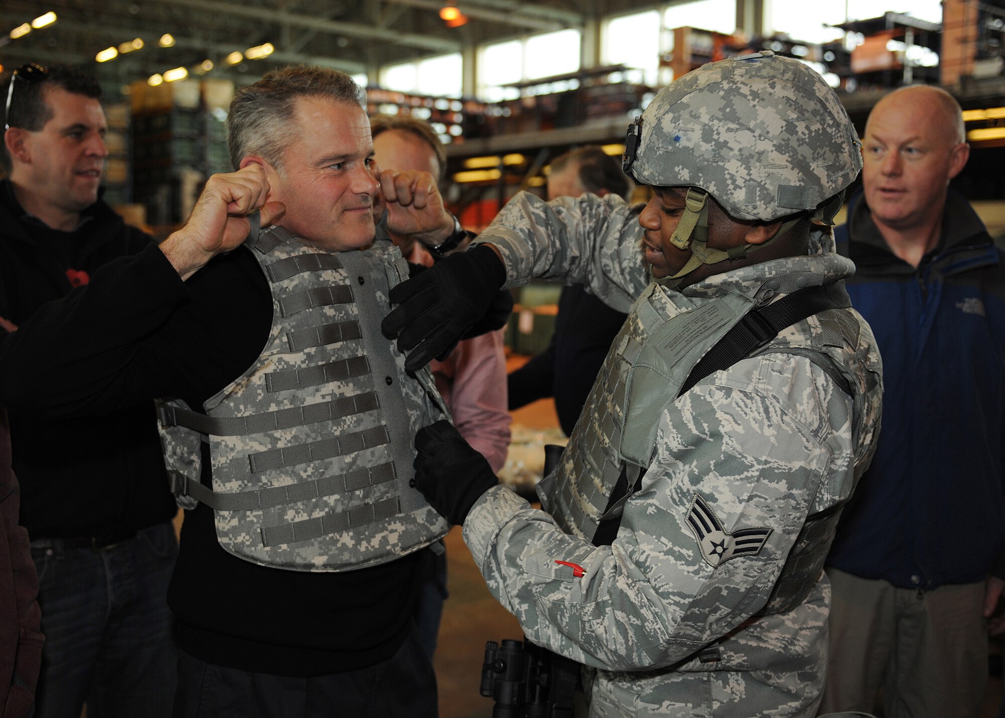 RAF MILDENHALL, England - Colin Aves, 100th Maintenance Operations Squadron honorary commander, is fitted for an individual protective equipment vest here by Senior Airman Valente Anderson, 100th Logistics Readiness Squadron individual protective equipment journeyman, Nov. 4, 2010.  The association between base commanders and their honorary commanders contributes to fostering and maintaining healthy British-American relations.  (U.S. Air Force photo/Senior Airman Tabitha M. Lee)  
