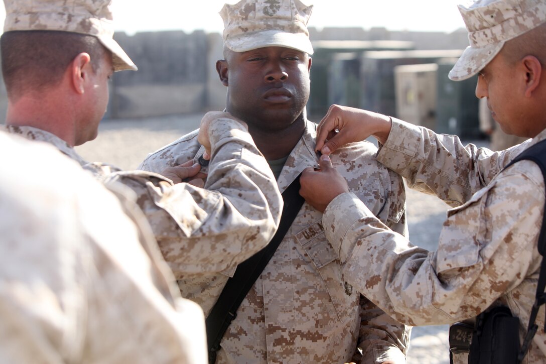 Marine Corps Gunnery Sgt. Victor Leaños, right, pins chevrons on the uniform of Marine Corps Staff Sgt. Otis B. Karngbaye, center, during a promotion ceremony at Camp Leatherneck, Afghanistan, Nov. 1, 2010. Leaños was one of Karngbaye’s drill instructors when he attended recruit training in August 2002. U.S. Marine Corps photo by Lance Cpl. Kenneth Jasik 