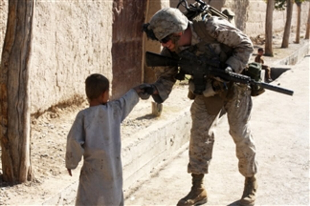 U.S. Marine Corps Lance Cpl. Steven J. Zandstra, with Police Adviser Team 1, 3rd Battalion, 5th Marine Regiment, Regimental Combat Team 2, shakes hands with an Afghan child during a security patrol with Afghan Uniformed Police officers through the northern bazaar in Sangin, Afghanistan, on Nov. 1, 2010.  The battalion was one of the combat elements of Regimental Combat Team 2, whose mission was to conduct counterinsurgency operations with the International Security Assistance Force.  