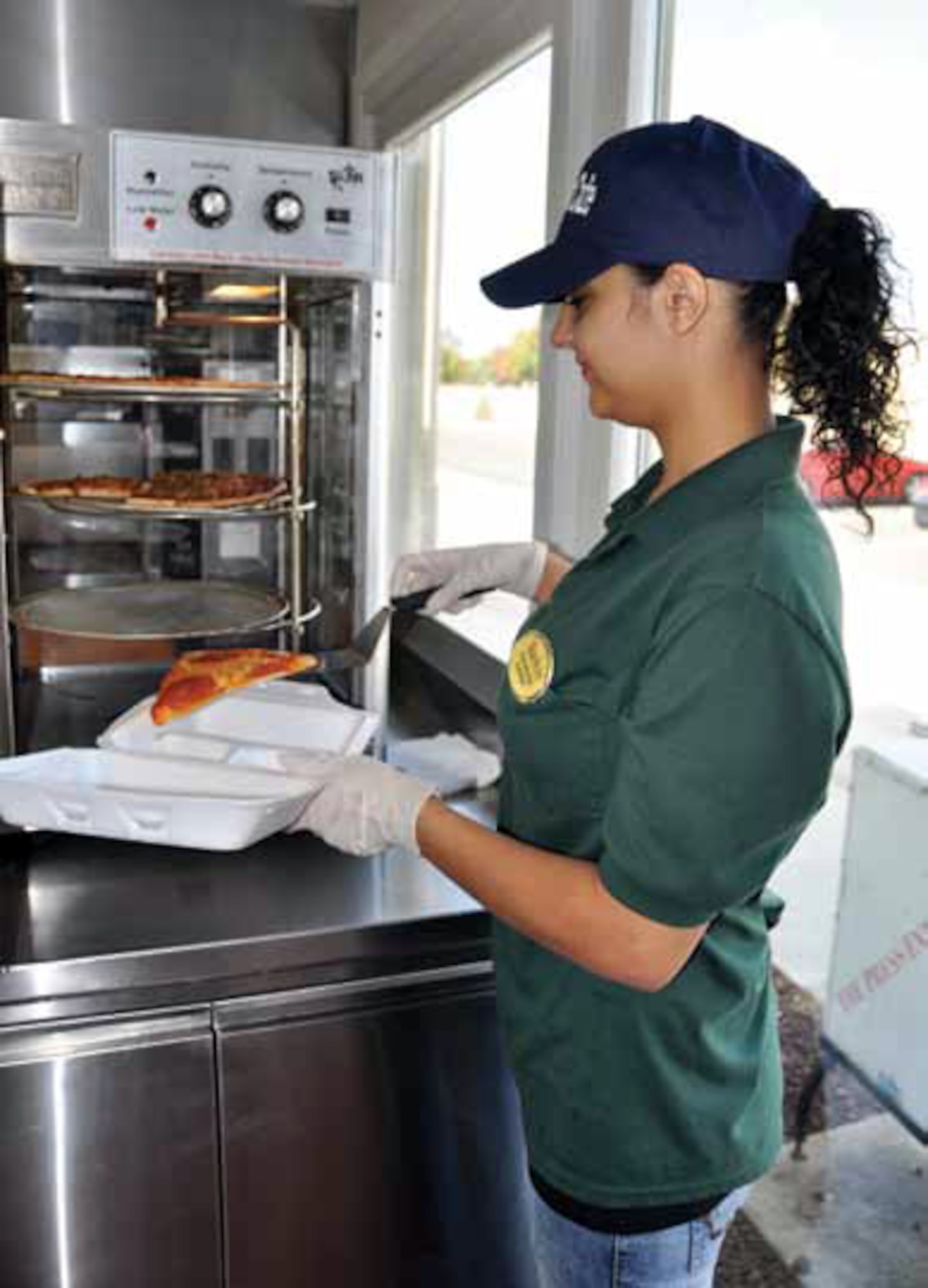 Oya Boyraz serves a slice of pizza at the BackStreet Cafe. Boyraz is the daughter of a March reservist and a long time Hap Arnold Club employee. (U.S. Air Force photo by Megan Just)
