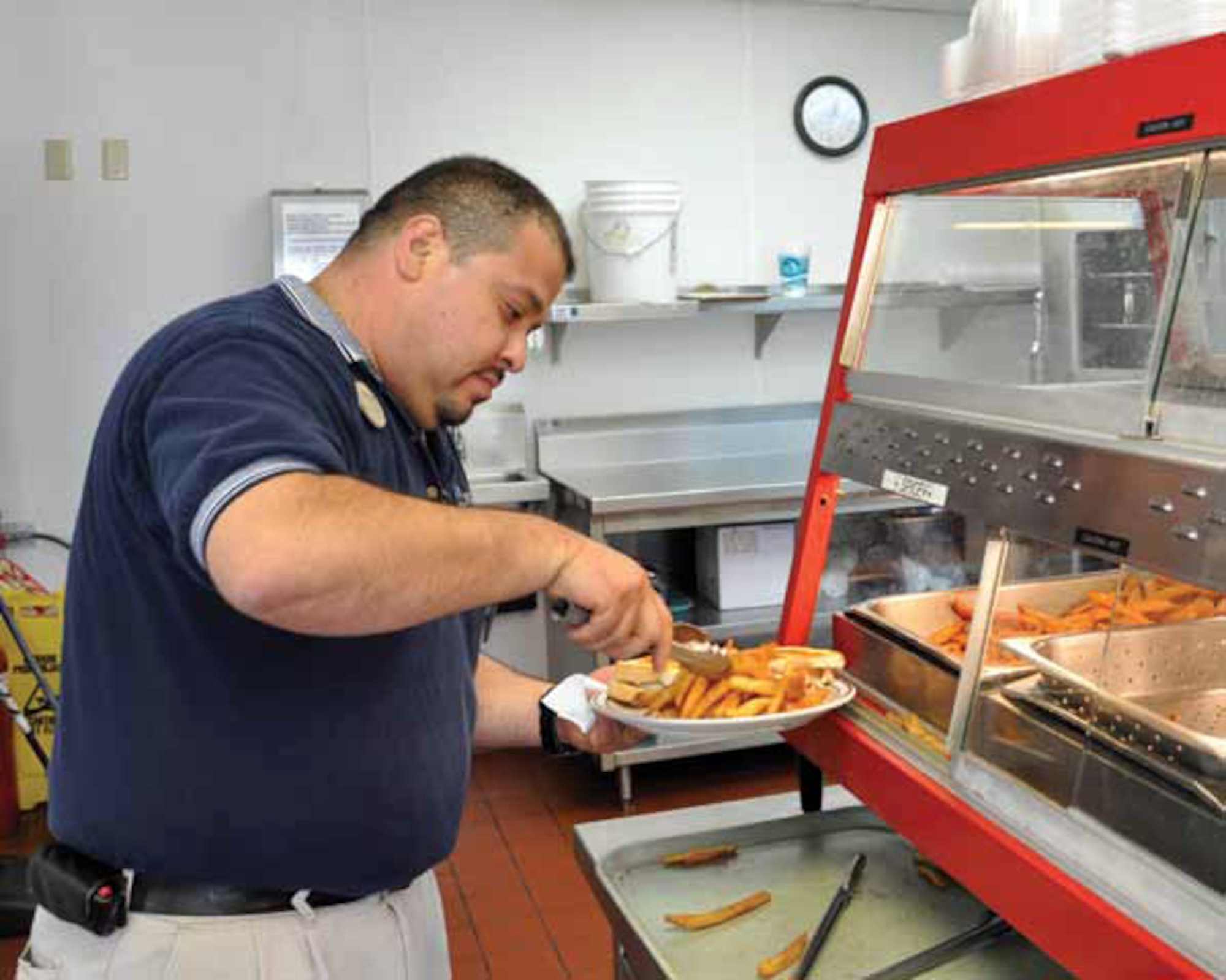 BackStreet Cafe Manager Gabriel Aleman serves a helping of spicy fries. Aleman has been working at the cafe for two years. (U.S. Air Force photo by Megan Just)

