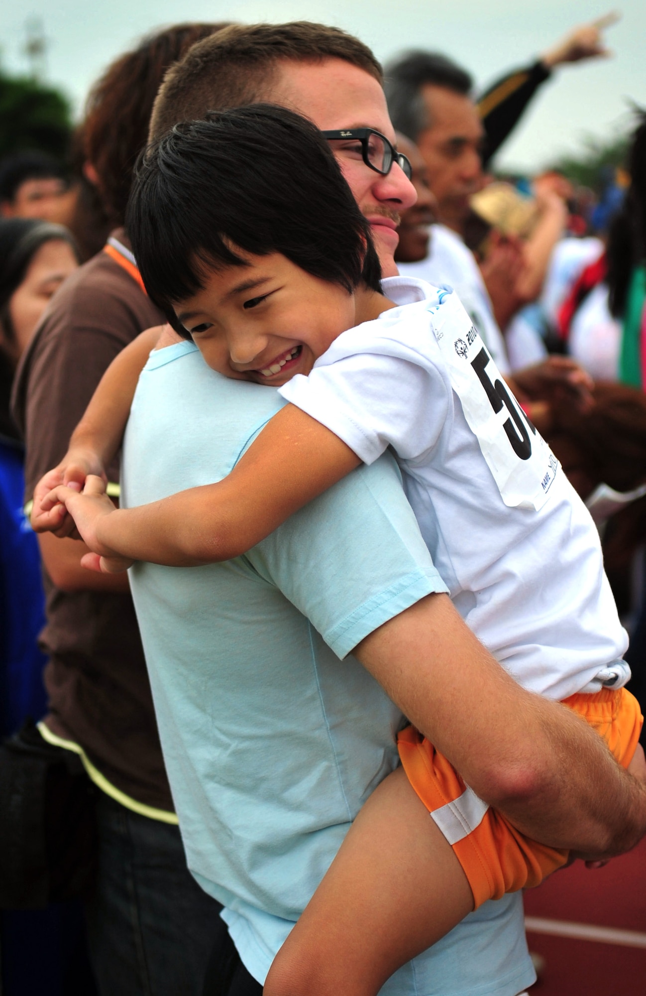 Airman 1st Class Matthew Renfro, an 18th Munitions Squadron volunteer hugger for the Kadena Special Olympics, gives Yuto Uehara a hug for luck before Yuto's next event. (U.S. Air Force photo/ Airman 1st Class Tara A. Williamson)