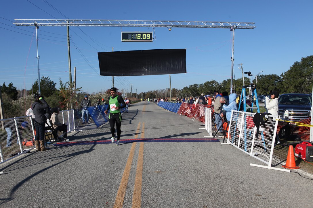 Shawn McKee, the winner of the Bay Six Battleship 5K race in Wilmington, N.C., crosses the finish line with a time of 18 minutes and 9 seconds, Nov. 7.   The five-kilometer race started just minutes after the 12th annual Battleship Half Marathon, and both races were dedicated to the men and women who have served and are currently serving in the United States Armed Forces.