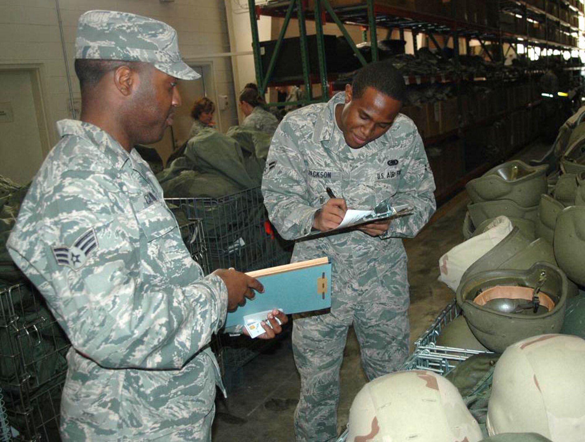 Senior Airman Ceasar Clyburn, 512th Airlift Wing Financial Management Office financial management technician, watches as Airman 1st Class Deont Jackson, 512th Logistics Readiness Flight material management technician, processes paperwork during the deployment exercise at Dover Air Force Base, Del., Nov. 6, 2010. The purpose of the exercise is to practice mobility processes and ensure wing readiness. (U.S. Air Force photo by Senior Airman Bhawan P. Singh/Released)