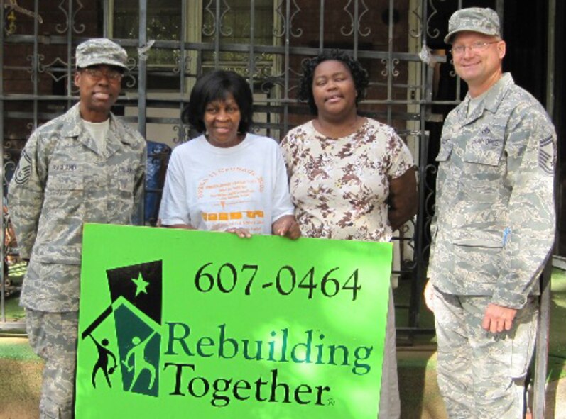 Senior Master Sgt. Treva Ragland, Ms. Treva Clark and her daughter, and Senior Master Sgt. David Liszeski pose in front of the Clark home on the day of the work project. Clark was recently named the winner of a home repair project from the Rebuilding Together charity and franchisees and associates of Choice Hotels' Econo Lodge and Rodeway Inn brands. (U.S. Air Force photo)