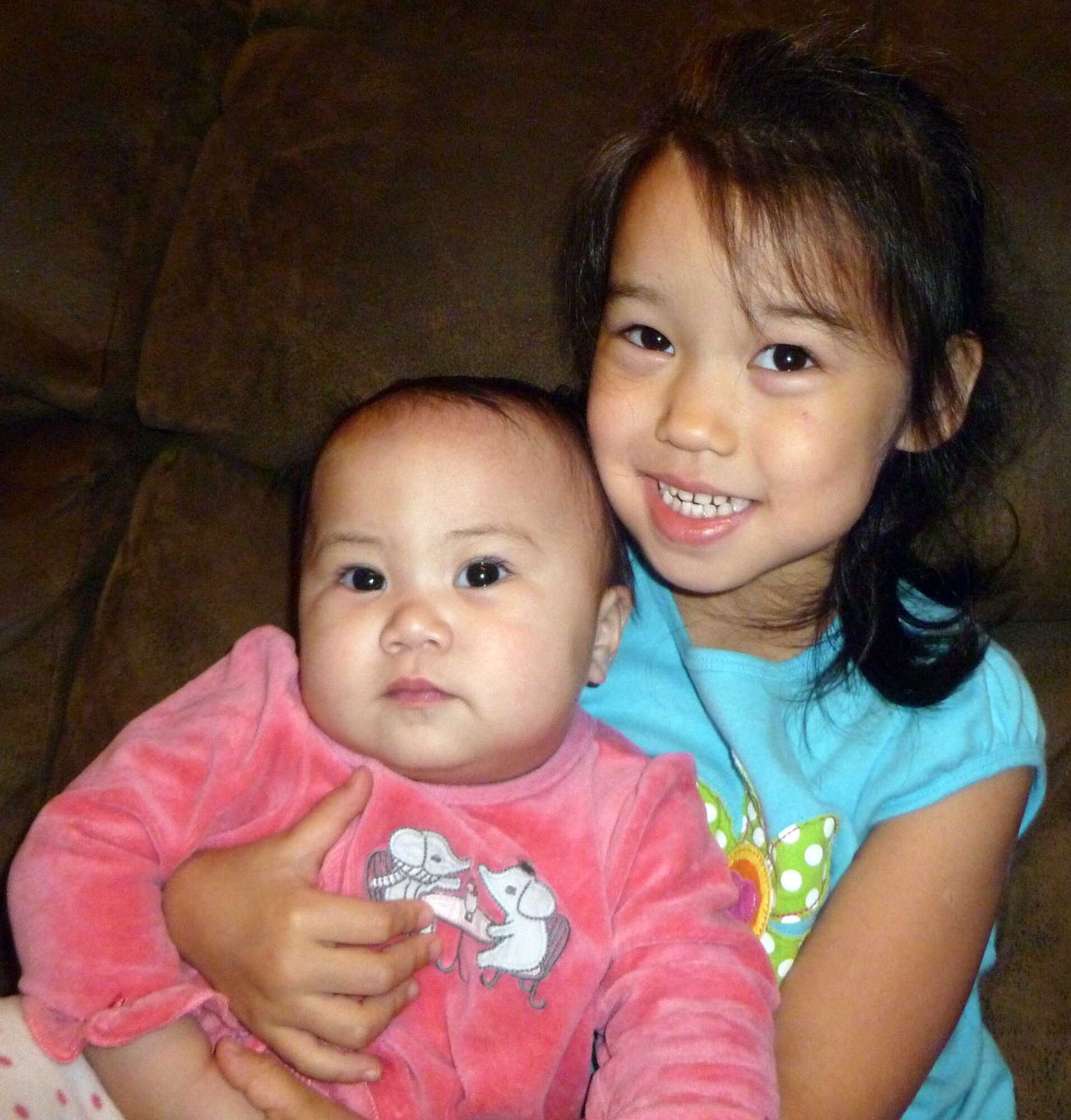 Ana (shown at right), and Abi Gustafson, daughters of Senior Master Sgt. Lance Gustafson, share a smile at the home of their adoptive parents in Harstine Island, Wash. Sergeant Gustafson is a loadmaster superintendent with the 313th Airlift Squadron.  He and his wife, Denice, also have three biological children.  "Kids bring a lot of joy to your life," said Sergeant Gustafson. (courtesy photo/Senior Master Sgt. Lance Gustafson)