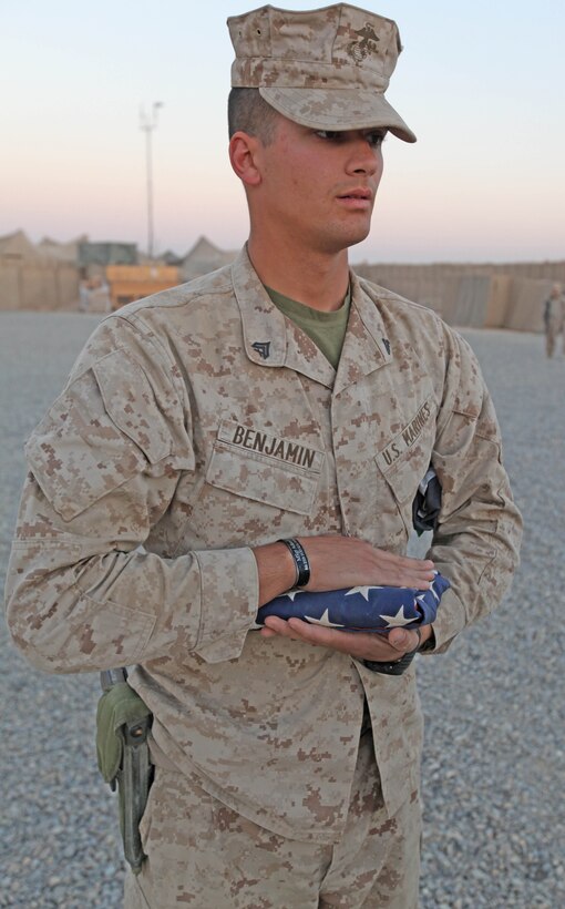 Cpl. Amos T. Benjamin, an infantry-man with 2nd Battalion, 9th Marine Regiment, stands at attention with a folded American Flag during evening colors at Marine Corps Forward Operating Base Camp Hansen, Helmand Province, Afghanistan, Nov. 8. Benjamin’s brother, Master Sgt. Adam F. Benjamin, was killed in Helmand Province last year and has used the deployment to honor his brother’s sacrifice.