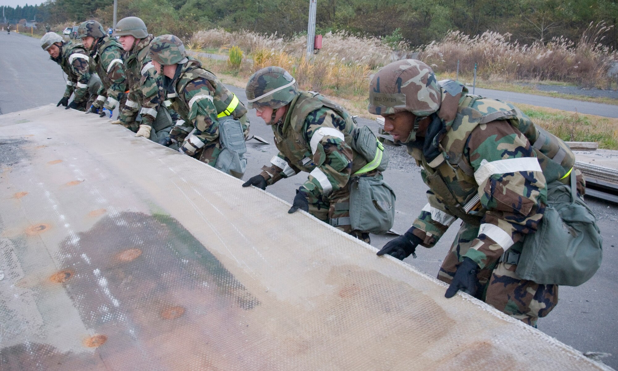 Airmen from the 35th Civil Engineer Squadron structures shop unfold a fiberglass mat, Nov. 8, 2010, at Misawa Air Base, Japan, during an operational readiness inspection.  The material, which was used to cover a patched simulated missile impact crater, is part of a process to rapidly repair flightlight damages. (U.S Air Force photo by Senior Airman Jessica Lockoski/Released)