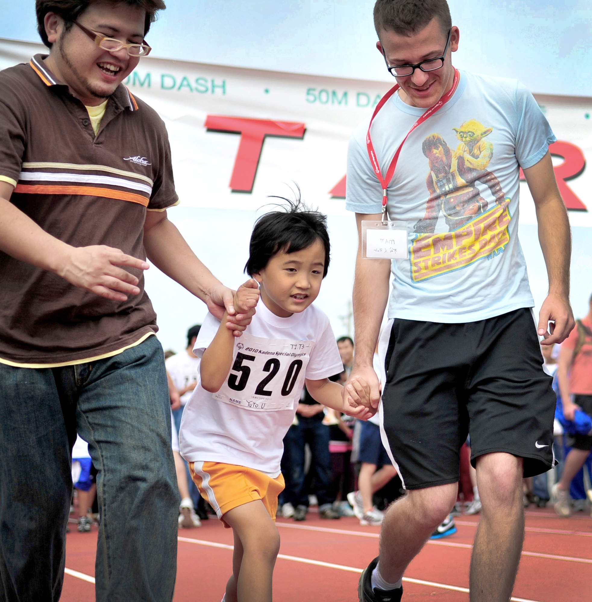 Airman 1st Class Matthew Renfro runs with Yuto Uehara and his father in the 30-meter dash Nov. 6, 2010, during the Kadena Special Olympics at Kadena Air Base, Japan. Airman Renfro was paired with Yuto, a young athlete during the event.  (U.S. Air Force photo/Airman 1st Class Tara A. Williamson) 
