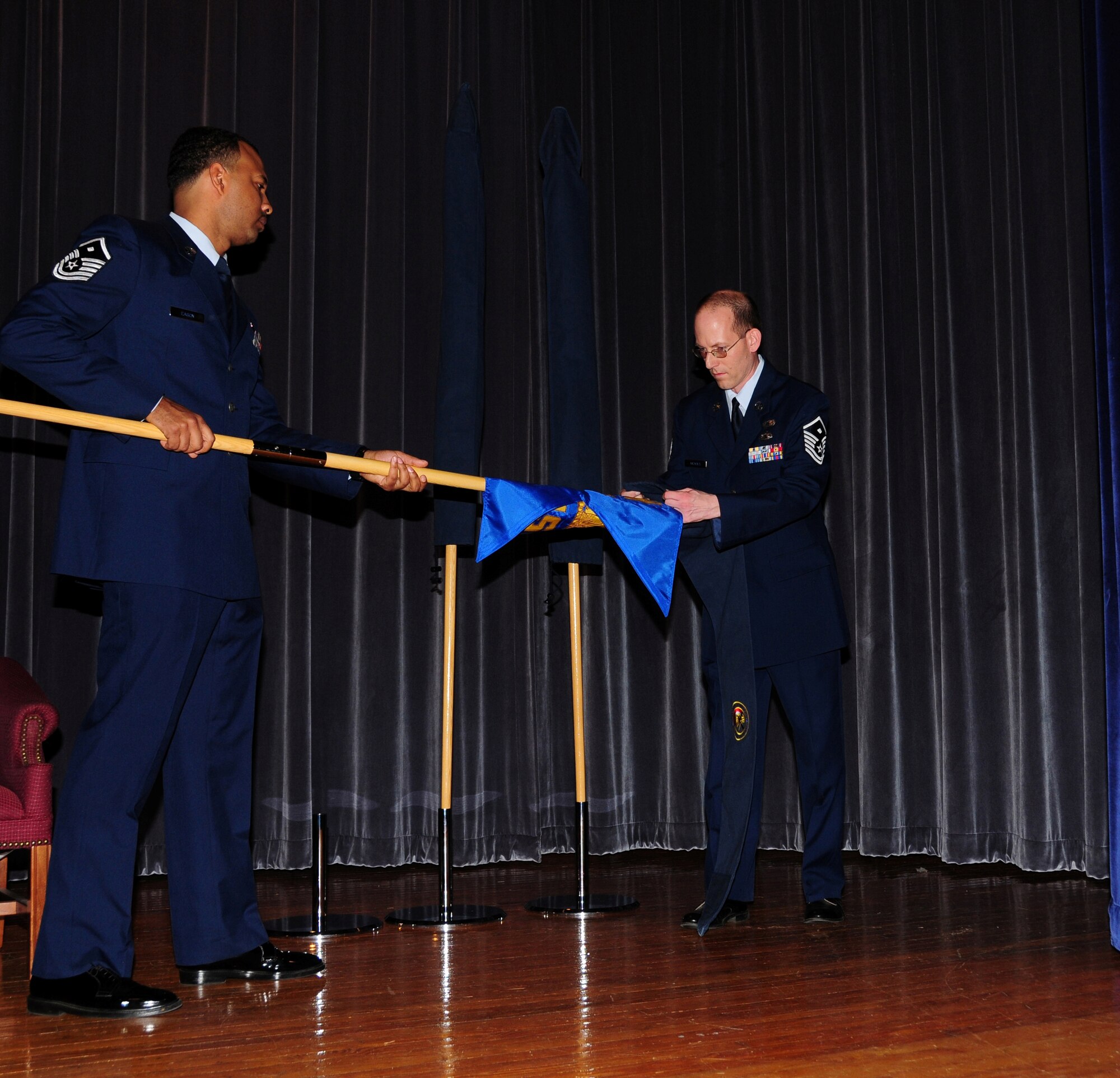 Master Sgt. Ken Eason 914th Force Support Squadron’s 1st Sgt. Unravels the squadrons guidon with Master Sgt. Kevin Nichols  1st Sgt. of the former 914th Services Squadron at the Roberts Joint Training Center November 7 on the Niagara Falls Air Reserve Station, Niagara Falls, N.Y. (Photo by Senior Airman Jessica Snow)