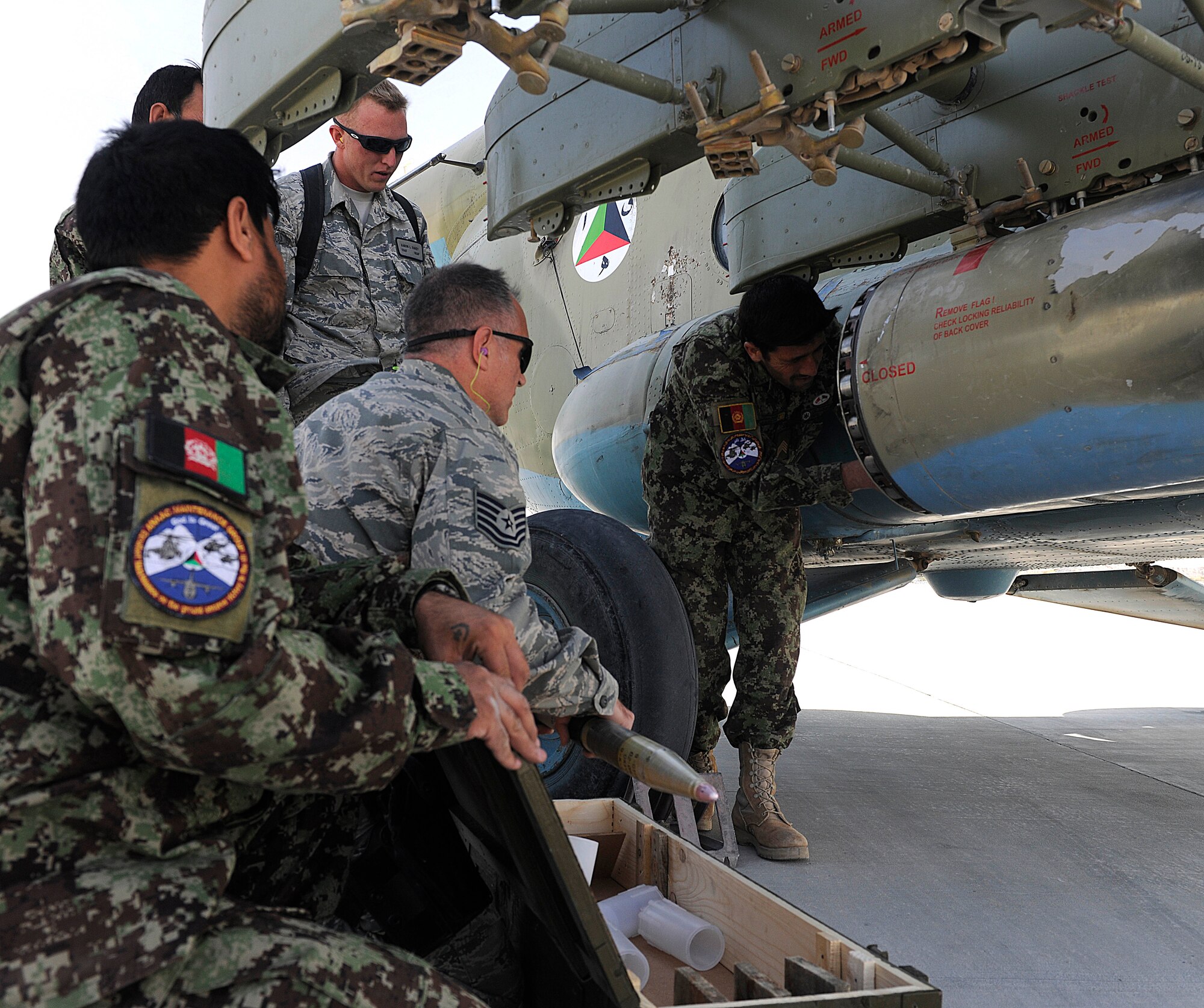KANDAHAR AIRFIELD, Afghanistan -- Tech. Sgt. Todd Zwickle and Staff Sgt. Aaron Davey, 738th Air Expeditionary Advisory Group, assist members of the Afghanistan National Army Air Force’s 305th Aircraft Maintenance Squadron in loading a 57mm rocket into Russian MI-17 helicopter’s rocket  before flying an escort mission Oct. 20. Sergeant Davey is deployed from the 5th Munitions Squadron at Minot Air Force Base, N.D. (U.S. Air Force photo/Senior Airman John Strong)