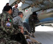KANDAHAR AIRFIELD, Afghanistan -- Tech. Sgt. Todd Zwickle and Staff Sgt. Aaron Davey, 738th Air Expeditionary Advisory Group, assist members of the Afghanistan National Army Air Force’s 305th Aircraft Maintenance Squadron in loading a 57mm rocket into Russian MI-17 helicopter’s rocket  before flying an escort mission Oct. 20. Sergeant Davey is deployed from the 5th Munitions Squadron at Minot Air Force Base, N.D. (U.S. Air Force photo/Senior Airman John Strong)