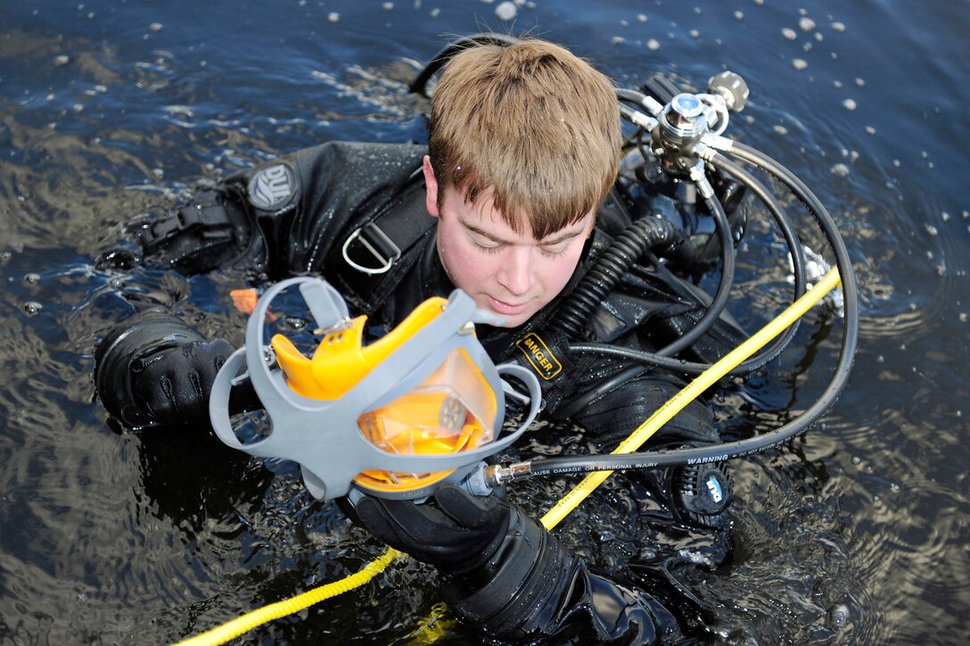 Senior Airman Mahonri Gibson prepares to don a full-faced scuba mask during a subsurface search and recovery exercise Oct. 20, 2010, at Stanford Training Area, England. Airman Gibson is a pararescueman with the 56th Rescue Squadron.  He is equipped with recovery dive equipment which includes a buoyancy compensator, a primary air source, a secondary emergency air source, a cold water regulator system and an exposure dry suit. (U.S. Air Force photo/Airman 1st Class Lausanne Morgan)