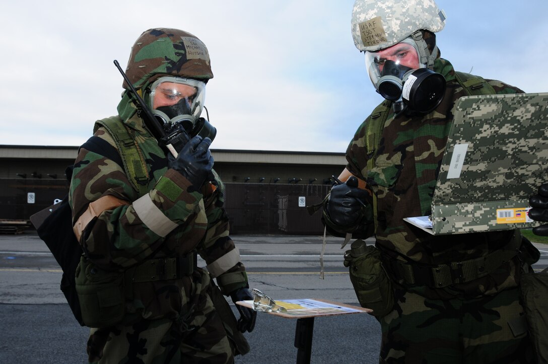 NIAGARA FALLS AIR RESERVE STATION, Ny - Niagara Falls Air Reserve Staion - Senior Airman Michael Hussar, 107th Airlift Wing aircrew flight equipment technician uses a radio to report the condition of the chemical agent detection paper, as Tech Sgt. Stephen Tirone, 107th Airlift Wing load master, documents the readings during an exercise November 6, 2010.   M8 paper is used to detect liquid, nerve and blister agents.  (U.S. Air Force photo by Senior Airman Jessica Mae Snow)