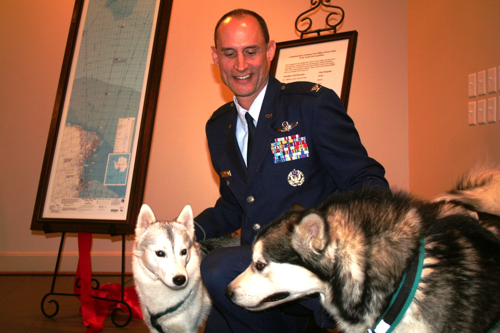 Col. Ronald Smith, Air National Guard advisor to the Air Mobility Command Director of Strategic Plans, Requirements and Programs at Scott Air Force Base, Ill., greets a Siberian Husky and an Alaskan Malamute after the presentation of a commemorative, centenary, first-edition Antarctic airway chart to the American Kennel Club Museum of the Dog in Saint Louis, Mo., on Nov. 2, 2010. The chart, created by Colonel Smith who was commander of Operation Deep Freeze from 2005 to 2008, shows “Airway 338” waypoints with each waypoint named after sled dog teams of Norwegian explorer Roald Amundsen and the pony pack team of British explorer Capt. Robert Falcon Scott. The aeronautical chart is used in international flight navigation from New Zealand to Antarctica -- especially for Operation Deep Freeze. (U.S. Air Force Photo/Master Sgt. Scott T. Sturkol)