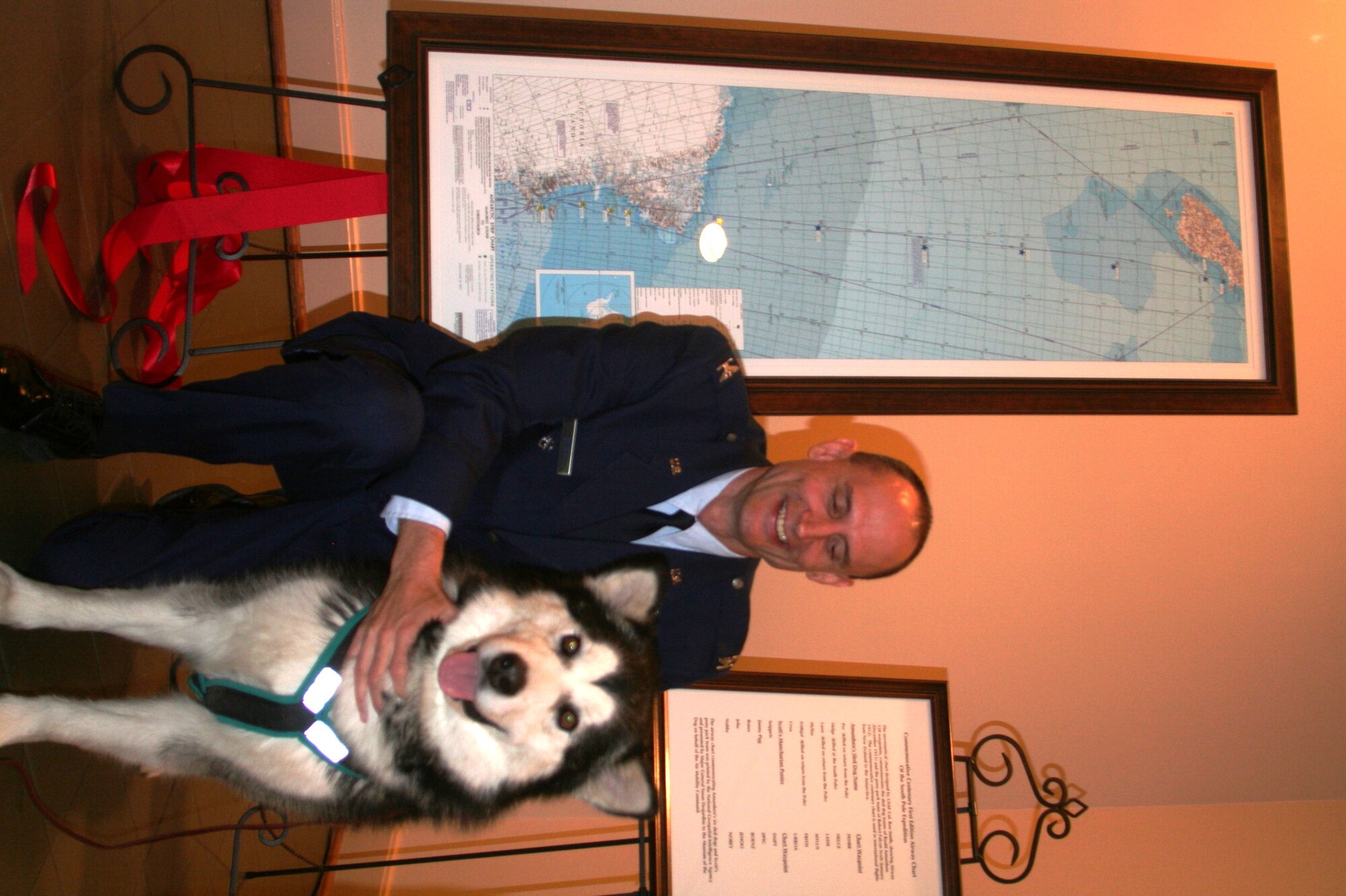 Col. Ronald Smith, Air National Guard advisor to the Air Mobility Command Director of Strategic Plans, Requirements and Programs at Scott Air Force Base, Ill., greets an Alaskan Malamute after the presentation of a commemorative, centenary, first-edition Antarctic airway chart that was presented to the American Kennel Club Museum of the Dog in Saint Louis, Mo., on Nov. 2, 2010. The chart, created by Colonel Smith who was commander of Operation Deep Freeze from 2005 to 2008, shows “Airway 338” waypoints with each waypoint named after sled dog teams of Norwegian explorer Roald Amundsen and the pony pack team of British explorer Capt. Robert Falcon Scott. The aeronautical chart is used in international flight navigation from New Zealand to Antarctica -- especially for Operation Deep Freeze. (U.S. Air Force Photo/Master Sgt. Scott T. Sturkol)