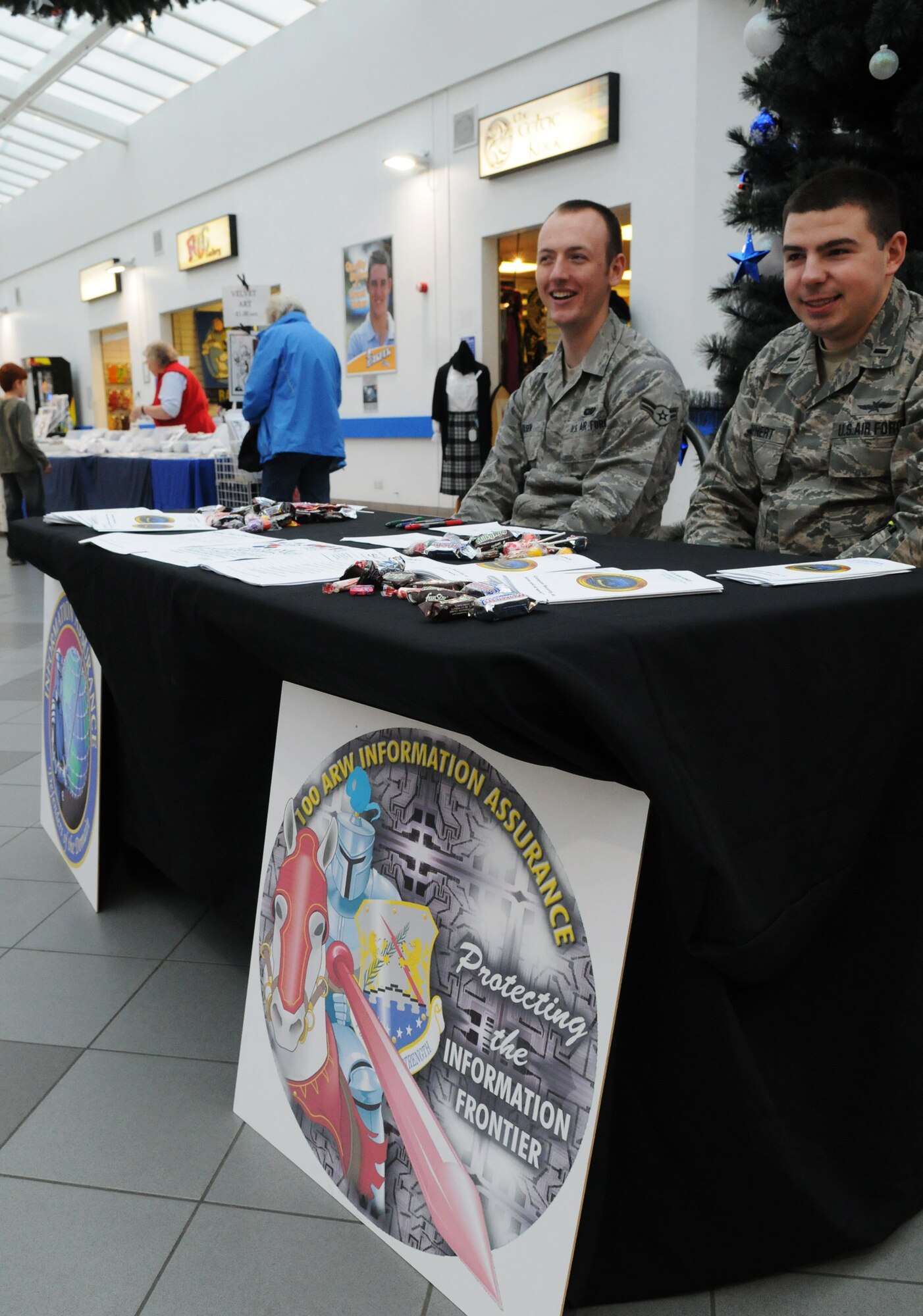 RAF MILDENHALL, England -- Airman 1st Class Joshua Olsen and 1st Lt. Joshua Bohnert, both 100th Communications Squadron communications professionals, provide education on information security at the BXtra here Nov. 5, 2010. This information booth served as RAF Mildenhall's finale for the 2010 U.S. Air Forces in Europe Information Assurance Awareness Campaign which aimed to increase consumer knowledge on computer security at home and work. (U.S. Air Force photo/Staff Sgt. Thomas Trower)
