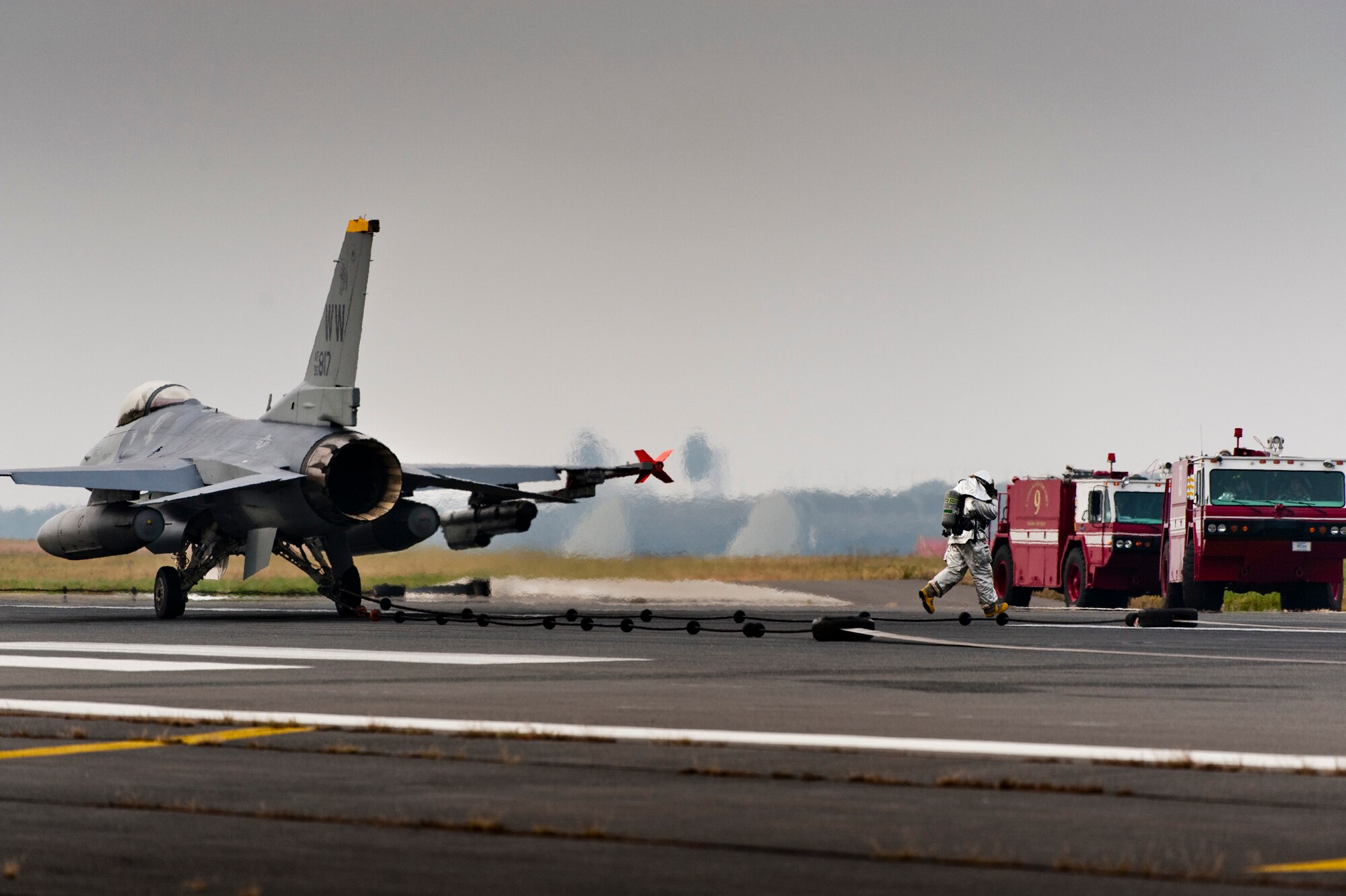A fireman from the 35th Civil Engineer Squadron hurries away from an F-16 Fighting Falcon after re-securing a barrier cable during an operational readiness exercise at Misawa Air Base, Japan, Nov. 8, 2010. The barrier cable provides pilots a secondary means to stop the aircraft in the event of an emergency. (U.S. Air Force photo by Staff Sgt. Samuel Morse/Released)