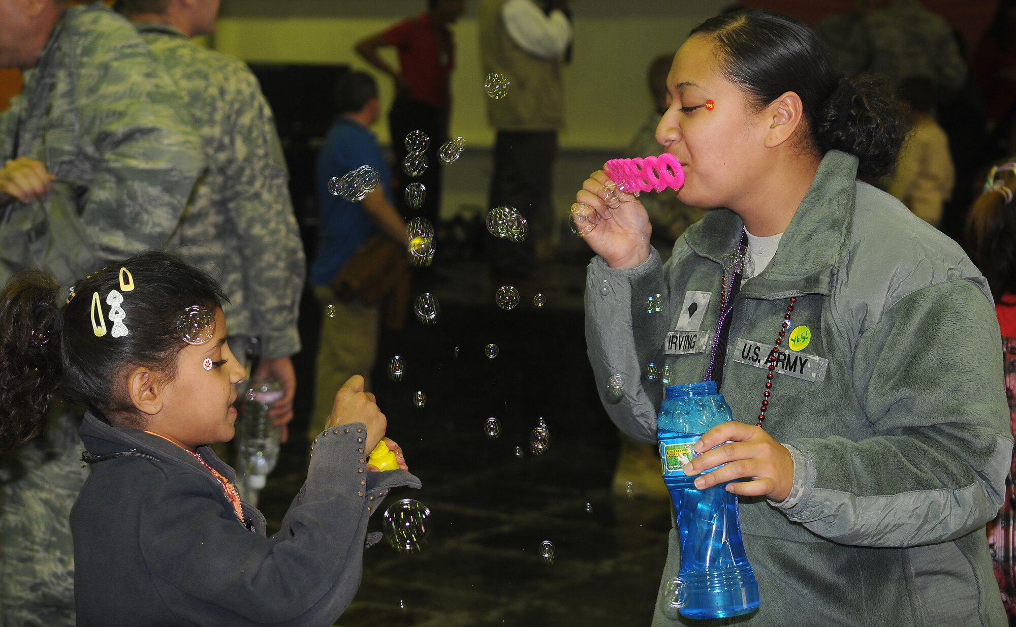 Spc. Natasha Irving 289th Quartermaster Company container repair yard admin clerk blows bubbles with an Iraqi child during Iraqi Kids Day Nov. 6, 2010, Joint Base Balad, Iraq. . Kids participated in games such as ping pong, soccer, bean bag toss, blowing bubbles, arts and crafts, and health and dental education and more during the five hour event. (U.S. Air Force Photo/ Senior Airman Marianne E. Lane)