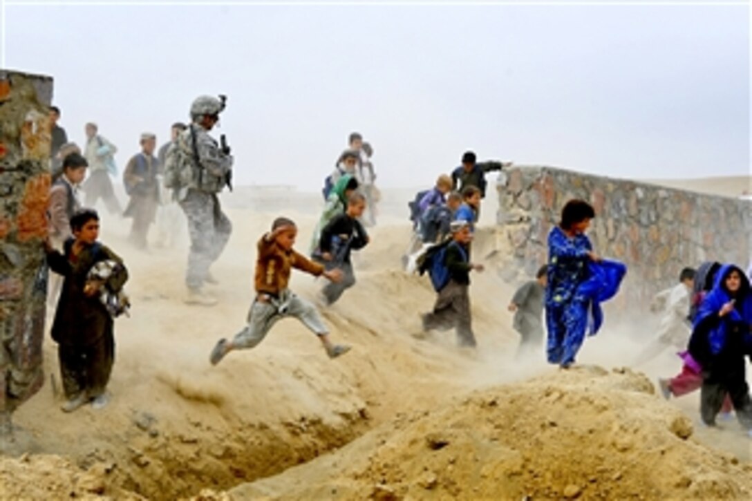 Escorted by dozens of children, U.S. Army Sgt. 1st Class Jeff Cesaitis exits the site of a future park during a site visit in Qalat, Afghanistan, on Oct. 28, 2010.  Cesaitis is assigned to the Zabul Provincial Reconstruction Team security force.  