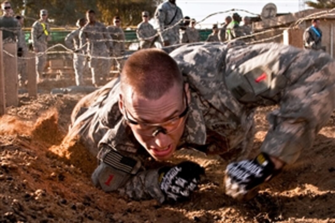 U.S. Army Sgt. Derek Czerniak crawls under a barbed wire obstacle during Demon Fury, a competition designed to test the full spectrum of soldiers' combat skills on Camp Taji, Iraq, Nov. 7, 2010. Czerniak is assigned to the 1st Infantry Division's Enhanced Combat Aviation Brigade.