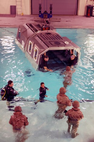 Instructors at the Water Survival Training Facility aboard Camp Lejeune, N.C., help Marines with Combat Logistics Regiment 2, 2nd Marine Logistics Group, enter the Modular Amphibious Egress Trainer during a training event Nov. 9, 2010. As the helo is submerged under water, a group of six Marines or sailors inside make their way out of the helicopter through one of the unlocked hatches located throughout the simulated aircraft.  (U.S. Marine Corps photo by Pfc. Franklin E. Mercado)