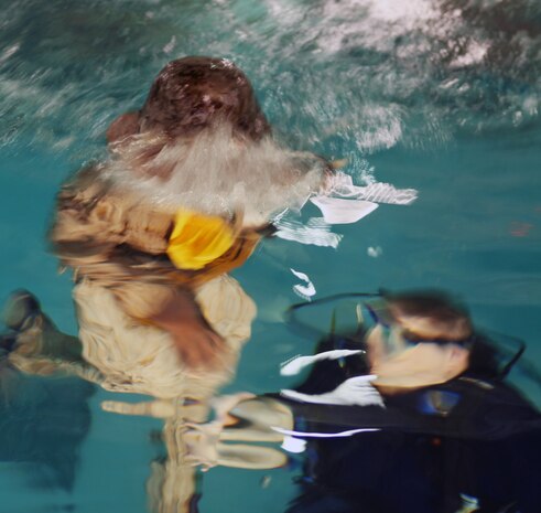 A diver at the Water Survivor Training Facilities helps a Marine with Combat Logistics Regiment 2, 2nd Marine Logistics Group, during a Modular Amphibious Egress Trainer exercise aboard Camp Lejeune, N.C., Nov. 9, 2010. As the helo is submerged under water, a group of six Marines or sailors inside make their way out of the helicopter through one of the unlocked hatches located throughout the simulated aircraft.   (U.S. Marine Corps photo by Pfc. Franklin E. Mercado)