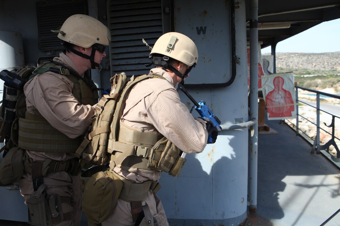 Corporal Britt Wade, left, and Sergeant Christopher Flynn, both members of 26th Marine Expeditionary Unit's Maritime Interception Operations assault force,  practice rounding corners while conducting tactical sweep techniques aboard HNS Aris at Souda Bay, Crete, Greece, Nov. 9, 2010. 26th MEU is currently embarked aboard the ships of Kearsarge Amphibious Ready Group and conducting training in the 5th Fleet area of responsibility.