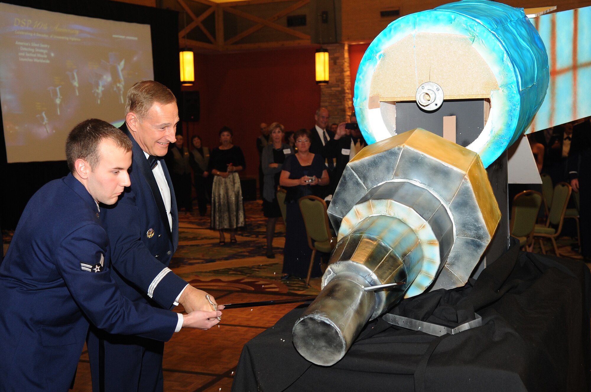 BUCKLEY AIR FORCE BASE, Colo.--Maj. Gen. Michael J. Basla, vice commander of  Air Force Space Command and A1C John Draper, the youngest Airman assigned to the 2nd Space Warning Squadron at Buckley Air Force Base share the honors of cutting up the mock up of the Defense Support Program (DSP) cake during the 40th Anniversary Gala on Nov. 6 2010. (U.S. Air Force Photo by Airman Manisha Vasquez) 