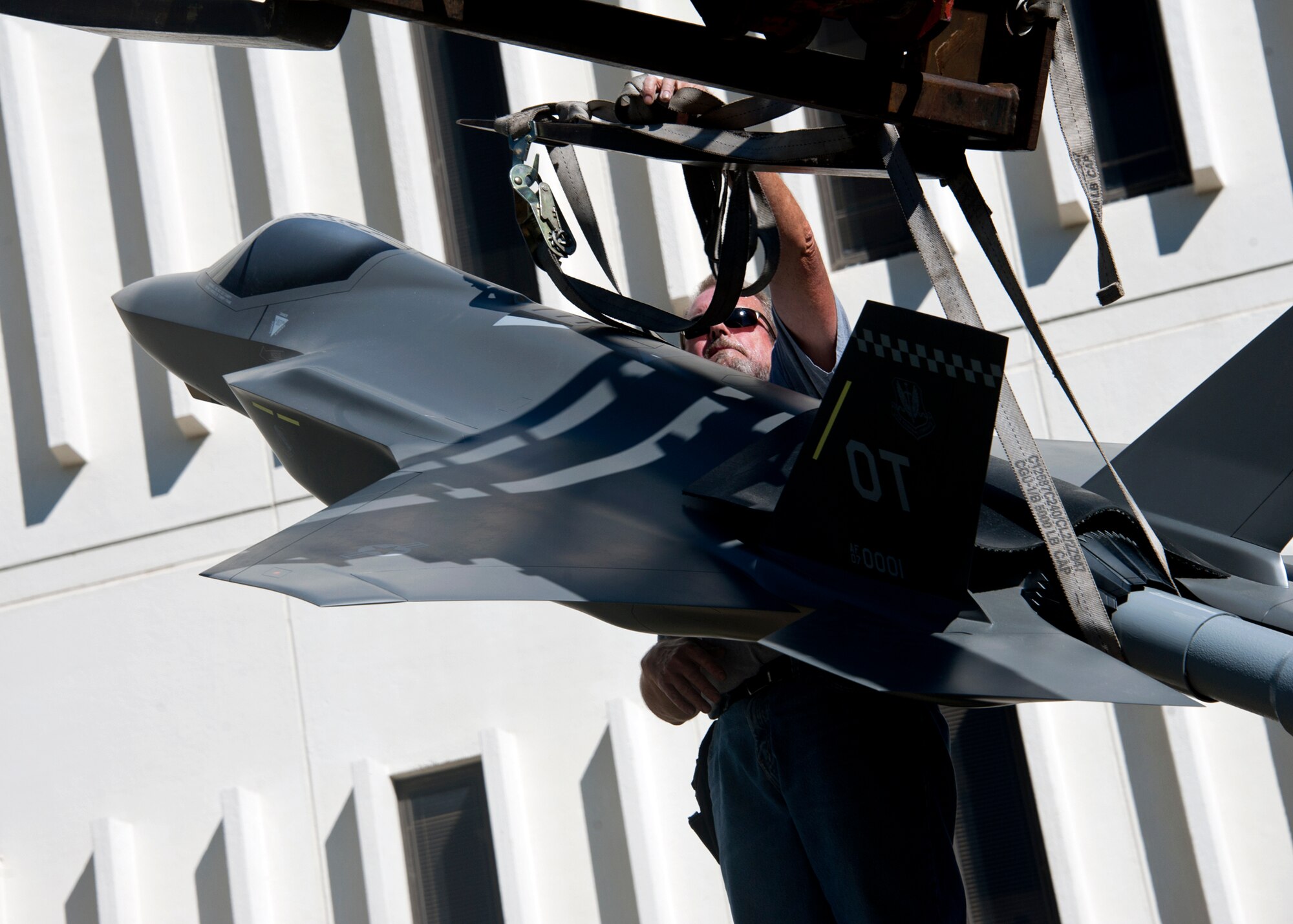 Robert Owens, 796th Civil Engineer Squadron, removes the straps from the new F-35 Lightning II static display in front of the 53rd Wing building Nov. 3.  The static display compliments the F-22 display on the left side of the entrance.  The 53rd Wing will be responsible for the operational testing of the F-35 aircraft.  (Air Force photo/ Samuel King Jr.)